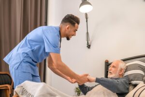 smiling medical worker lifting old man from bed 259150 63827