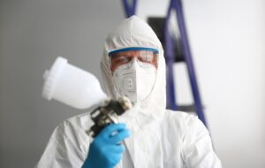 workman hold arm airbrush gun wearing protective suit 151013 58276